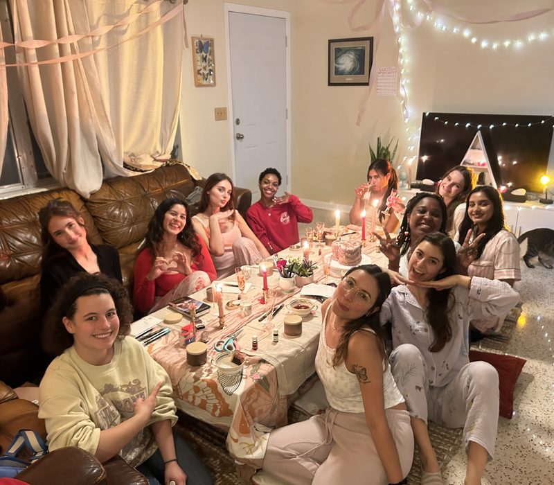 Mavens collective members gathered around a table, candles lit, smiling