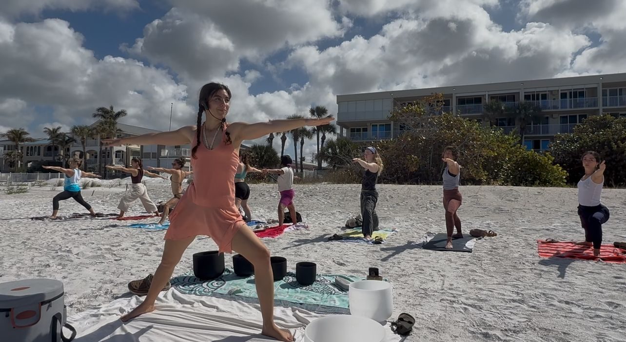 A group gathered on the beach for yoga and sound at sunrise